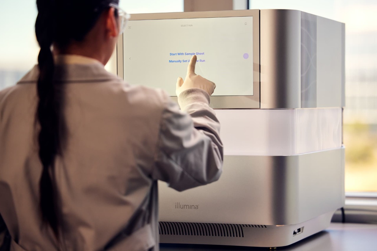 Female scientist, back view, standing in front of NextSeq 1000/2000, touch screen to start and select plan